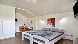 Ein Schlafzimmer mit einem Bett, einem Schreibtisch, einem Sessel, einem Fernseher und einem Bild an der Wand.