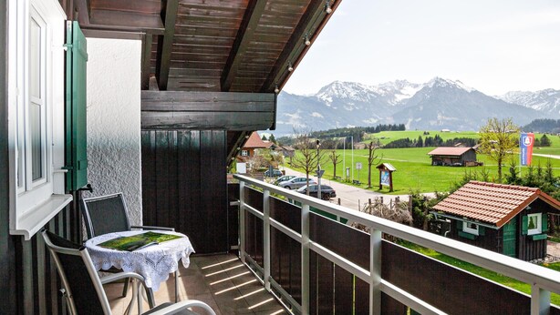 Ein Balkon mit Blick auf Berge, ein Tisch mit Tischdecke und ein Stuhl.