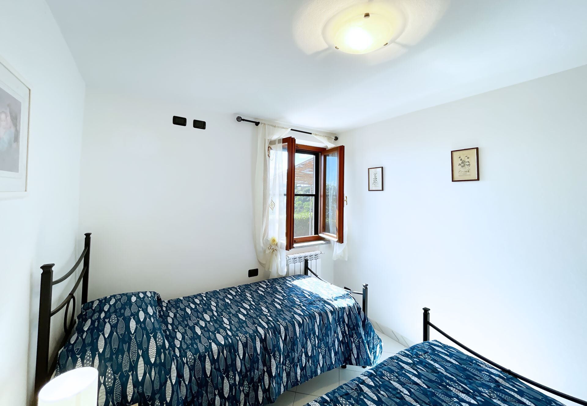 Una habitación pequeña y luminosa con cama, ventana y radiador.
