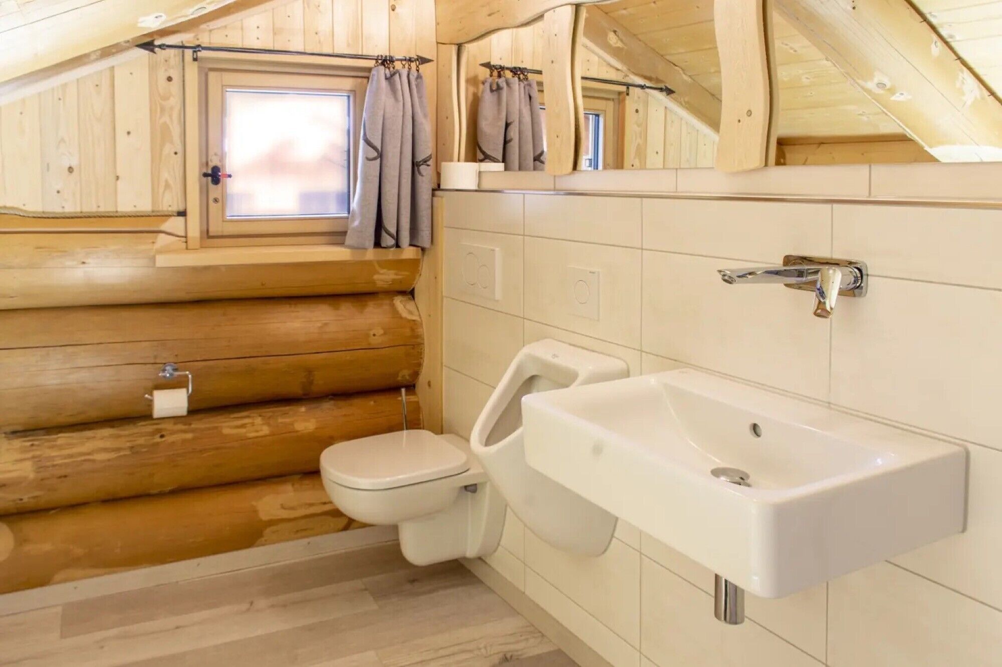 Een houten badkamer met toilet, wastafel en raam.