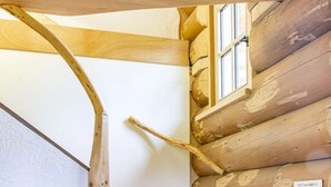Un escalier en colimaçon en bois, avec un mur blanc et une fenêtre.