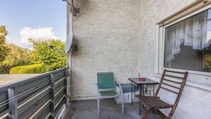 Un balcón con mesa, sillas y vistas al follaje circundante.