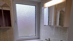 Ein Badezimmer mit Toilette, Waschbecken, Fenster und Spiegel.
