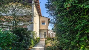 Un sendero conduce a un edificio de estilo arquitectónico tradicional, rodeado de abundante vegetación.