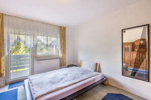 A bedroom with a bed, a window with curtains, a radiator, and a mirror on the wall. - Apartment 'Fewowellnesspalast' with Balcony and Wi-Fi (Bad nauheim)