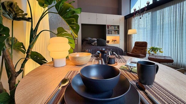 A modern room with a dining table set, a large plant, and a view of the outside. - Eichenwald Studio with Mountain View, Fireplace, Balcony, and Wi-Fi (Bad Herrenalb)