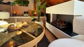 A modern living room with a glass coffee table, a fireplace, and a large plant. - Eichenwald Studio with Mountain View, Fireplace, Balcony, and Wi-Fi (Bad Herrenalb)