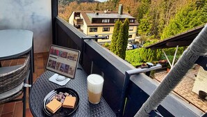 A balcony with a computer monitor, a glass of milk, and a plate of waffles. - Eichenwald Studio with Mountain View, Fireplace, Balcony, and Wi-Fi (Bad Herrenalb)