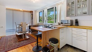 Una cocina moderna con una isla de madera, armarios blancos y un ventanal amplio.