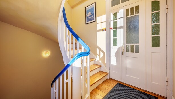 Una escalera con barandilla azul que conduce a una puerta con paneles de vidrio esmerilado.
