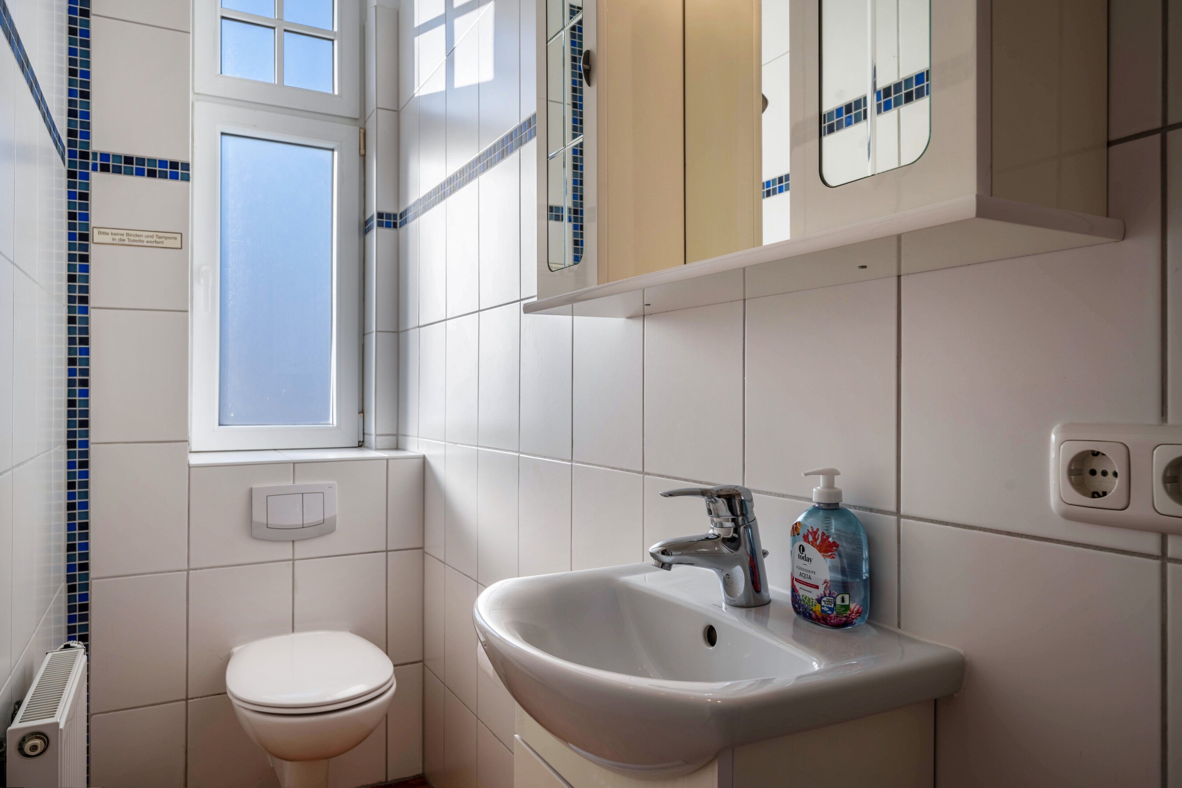 A bathroom with a toilet, sink, and mirror.