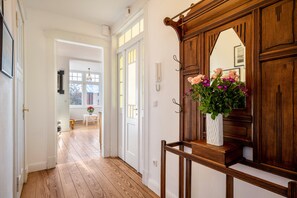 A hallway with wooden flooring, a white door, and a mirror with a wooden frame.