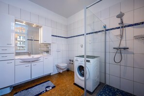 Un baño moderno con lavamanos, inodoro, lavadora y ducha.