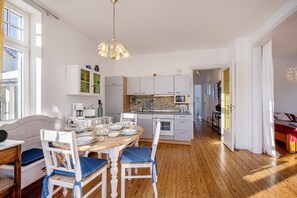 A modern kitchen with white cabinets, a wooden dining table, and blue chairs.