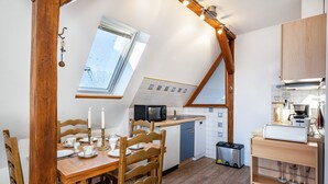 Cocina compacta con comedor, muebles de madera, microondas integrado y una ventana pequeña.