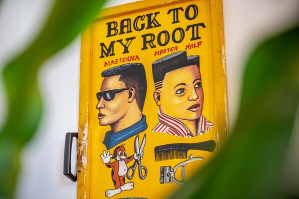 A yellow barber's chair with a sign reading 'BACK TO MY ROOT' and illustrations of a man and woman with a cartoon monkey.