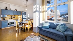 A compact living space with a kitchen, dining area, and a sofa by a window.