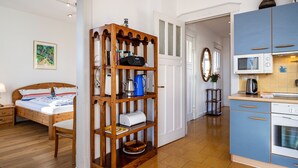A bedroom with a wooden bed, a bedside table, and a nightstand. There is a wooden shelf unit with various items on it.