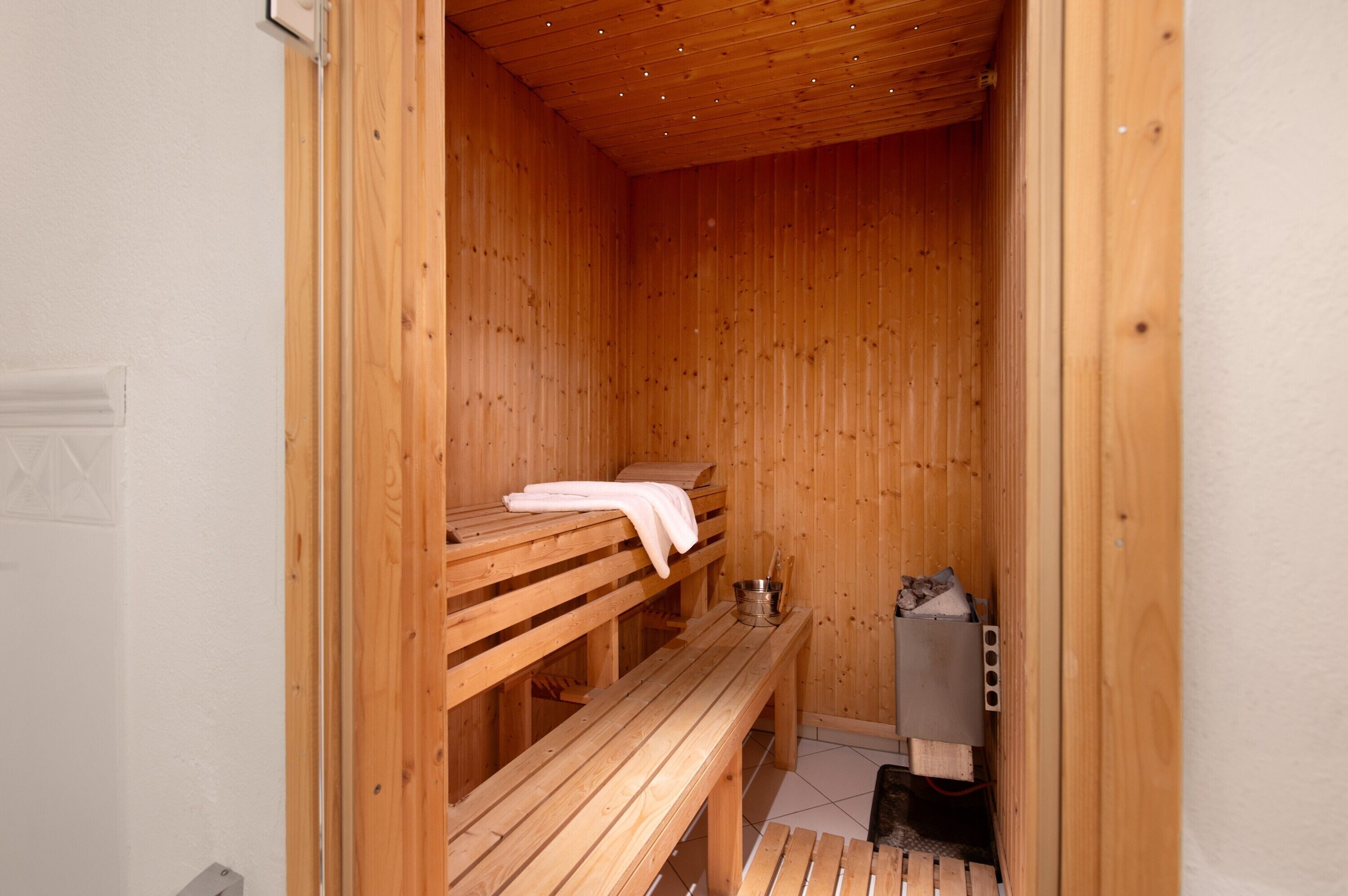 A sauna with wooden benches, a bench with a towel, and a heater.