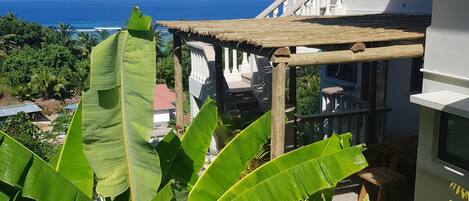 Una casa con balcón que ofrece vistas panorámicas del océano y abundante vegetación.
