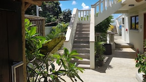 A covered outdoor area with a staircase leading to a building, surrounded by greenery. - Island Cove (Mahé Island)