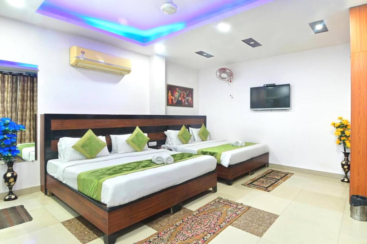 Habitación de hotel con dos camas, un televisor de pantalla plana, un equipo de aire acondicionado y almohadas decorativas.