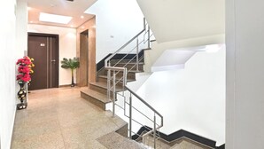 Un moderno vestíbulo de hotel con una escalera, una recepción y una planta en maceta.