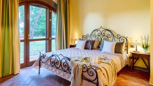 Un dormitorio con cama, cortinas, una ventana y una mesita de noche con lámpara.
