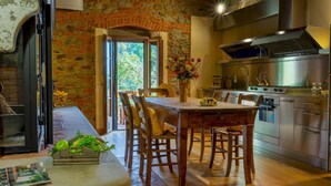 Una cocina rústica con pared de ladrillo, mesa de madera y electrodomésticos modernos.