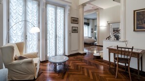 A spacious living room with a wooden herringbone floor, a round table, a sofa, and a chair. - Villa Liberty Albisola 6 2 Emma Villas (Albisola Superiore)