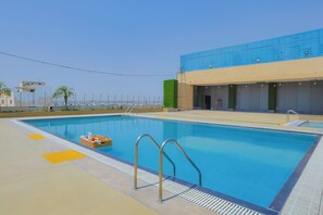Una piscina con agua cristalina azul, rodeada por un borde de baldosas blancas y amarillas.