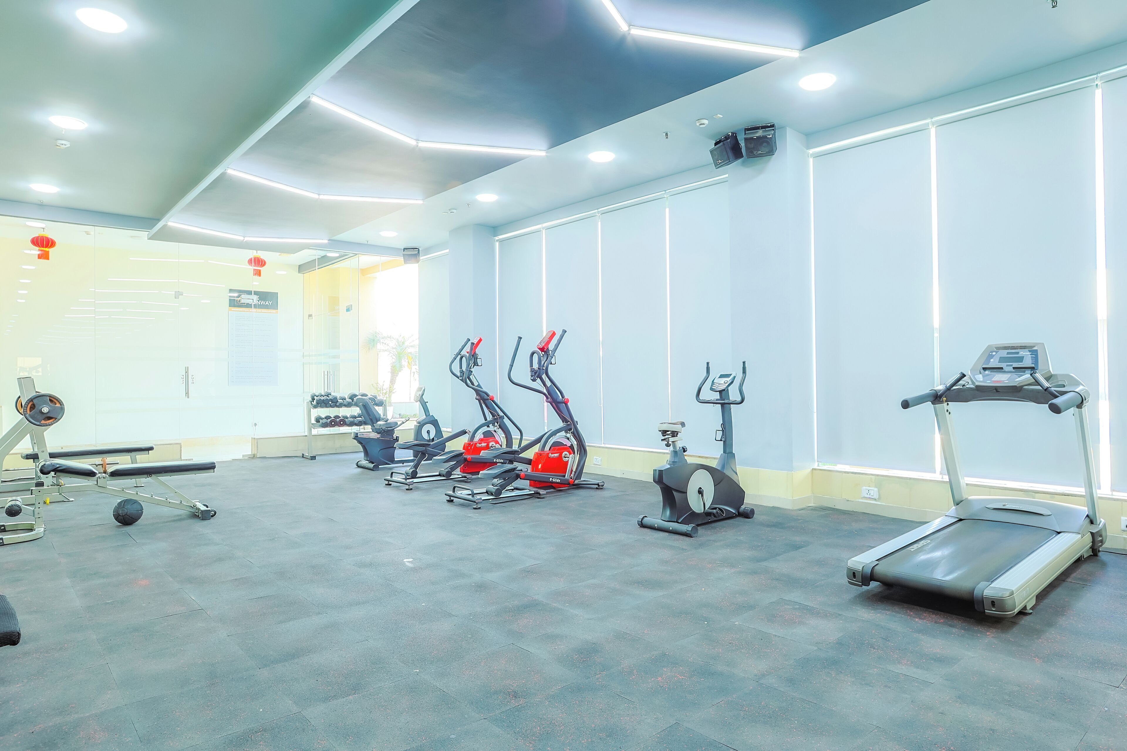 Une salle de sport équipée de tapis de course, de vélos elliptiques et de matériel de musculation.