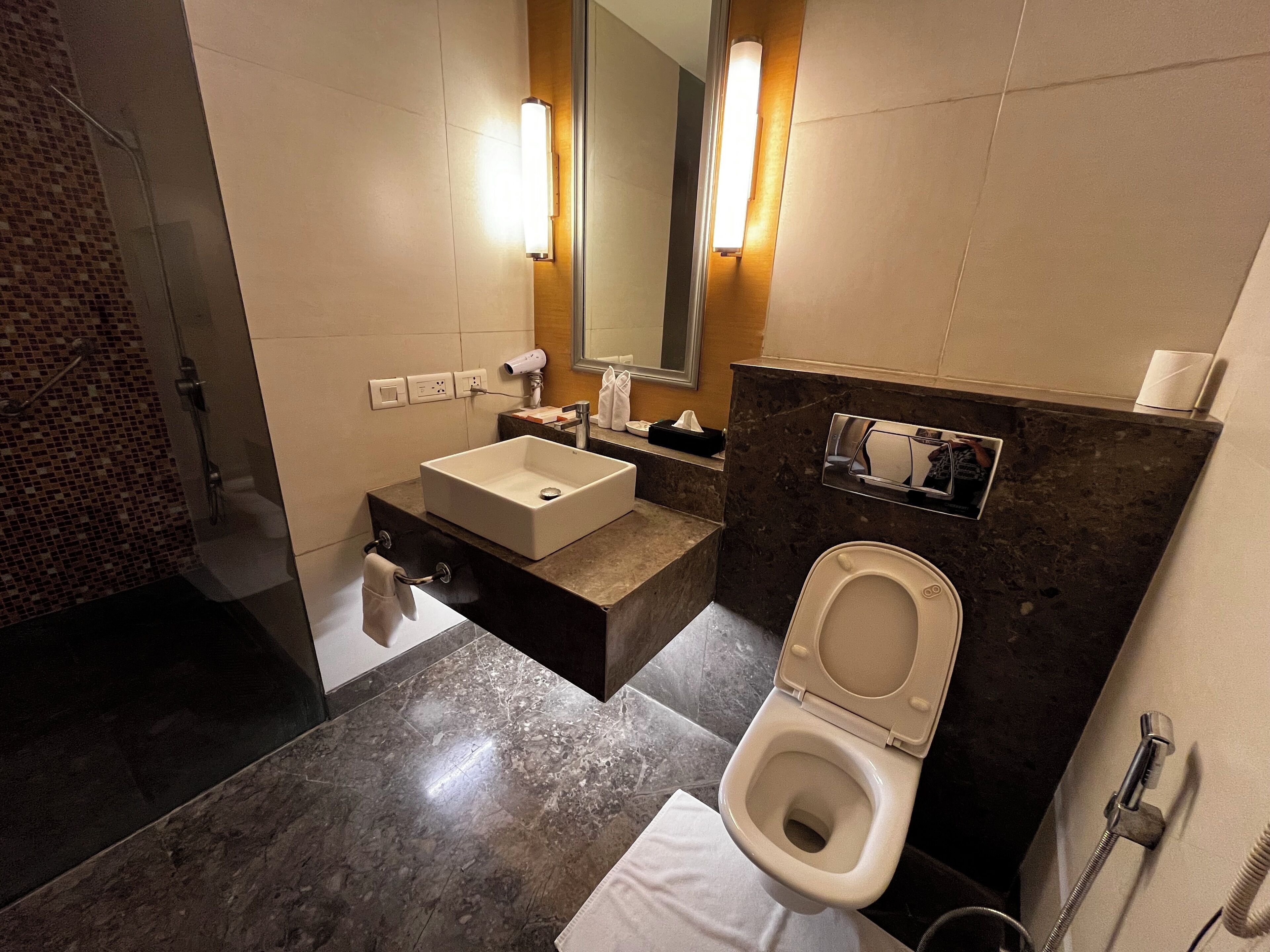 A modern bathroom with a sink, mirror, toilet, and shower.