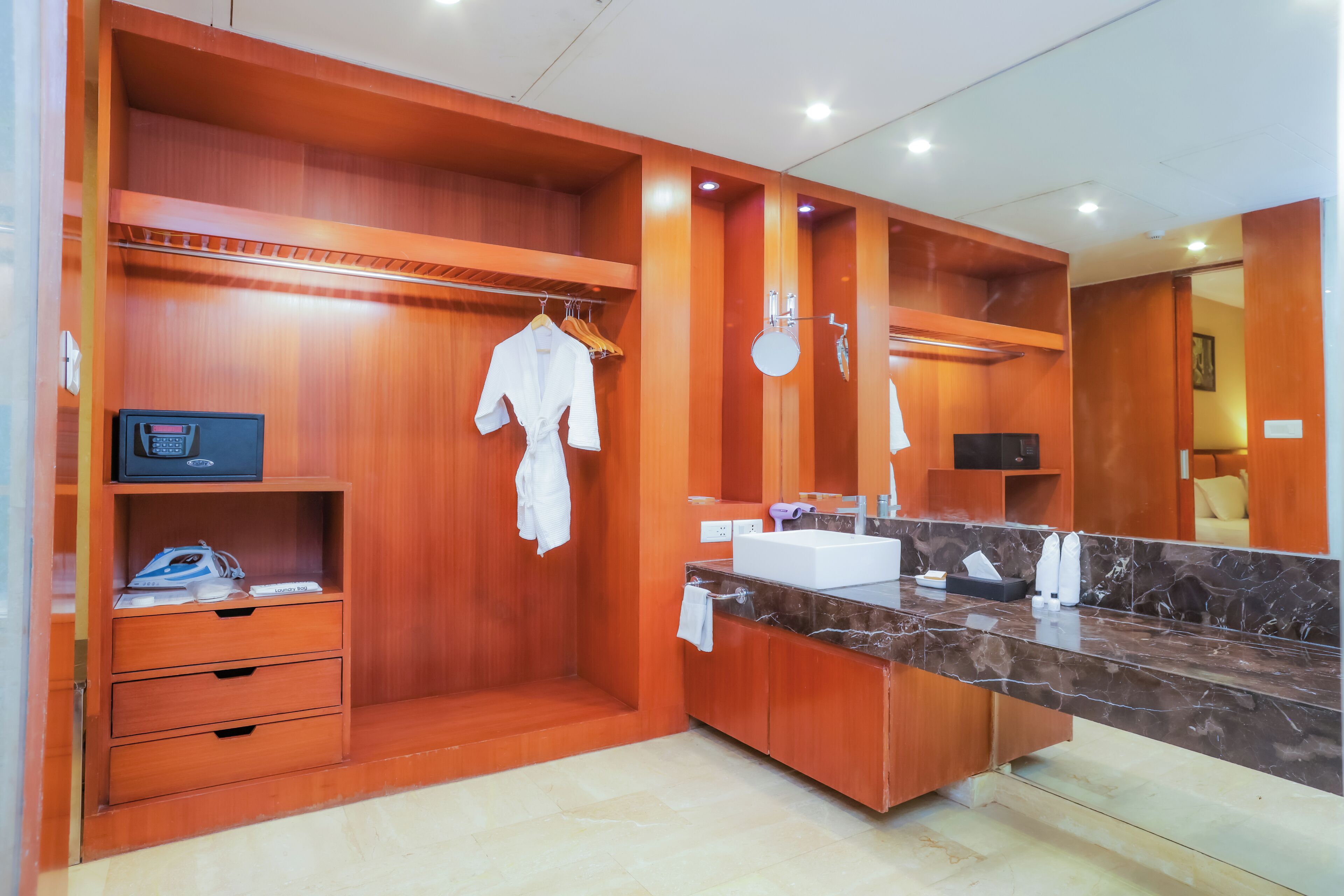 A modern bathroom with wooden cabinetry, a marble countertop, and a built-in mirror.