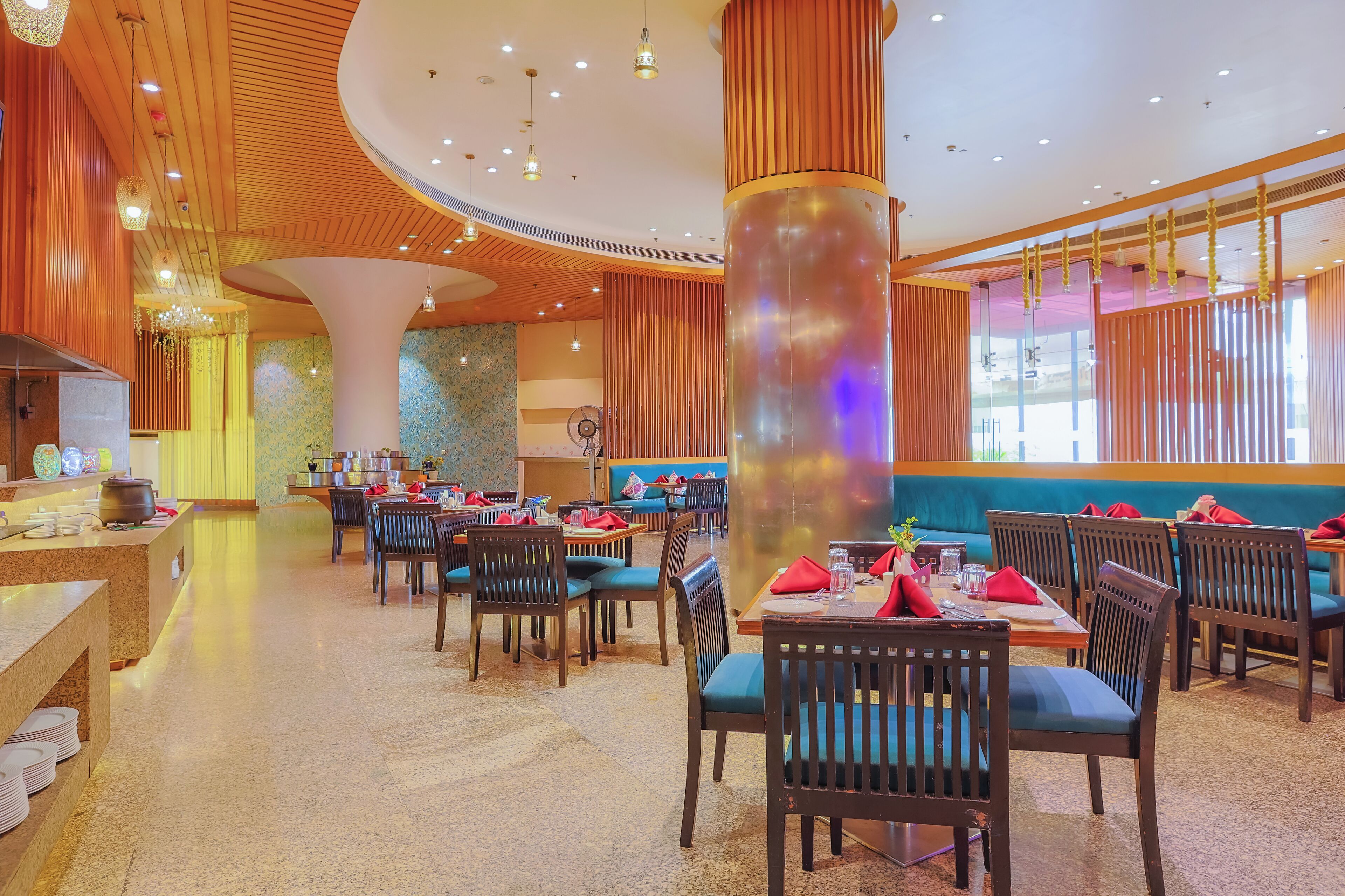 Un restaurant avec des murs lambrissés, des banquettes bleues rembourrées et une colonne centrale dotée d’une surface réfléchissante.