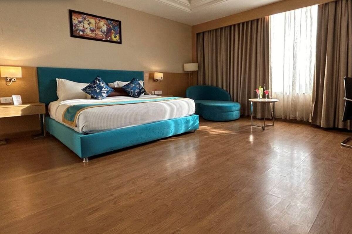 A hotel room with a large bed, a desk, a chair, and a small table.