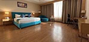 Una habitación de hotel con una cama grande, un escritorio, una silla y una mesita.