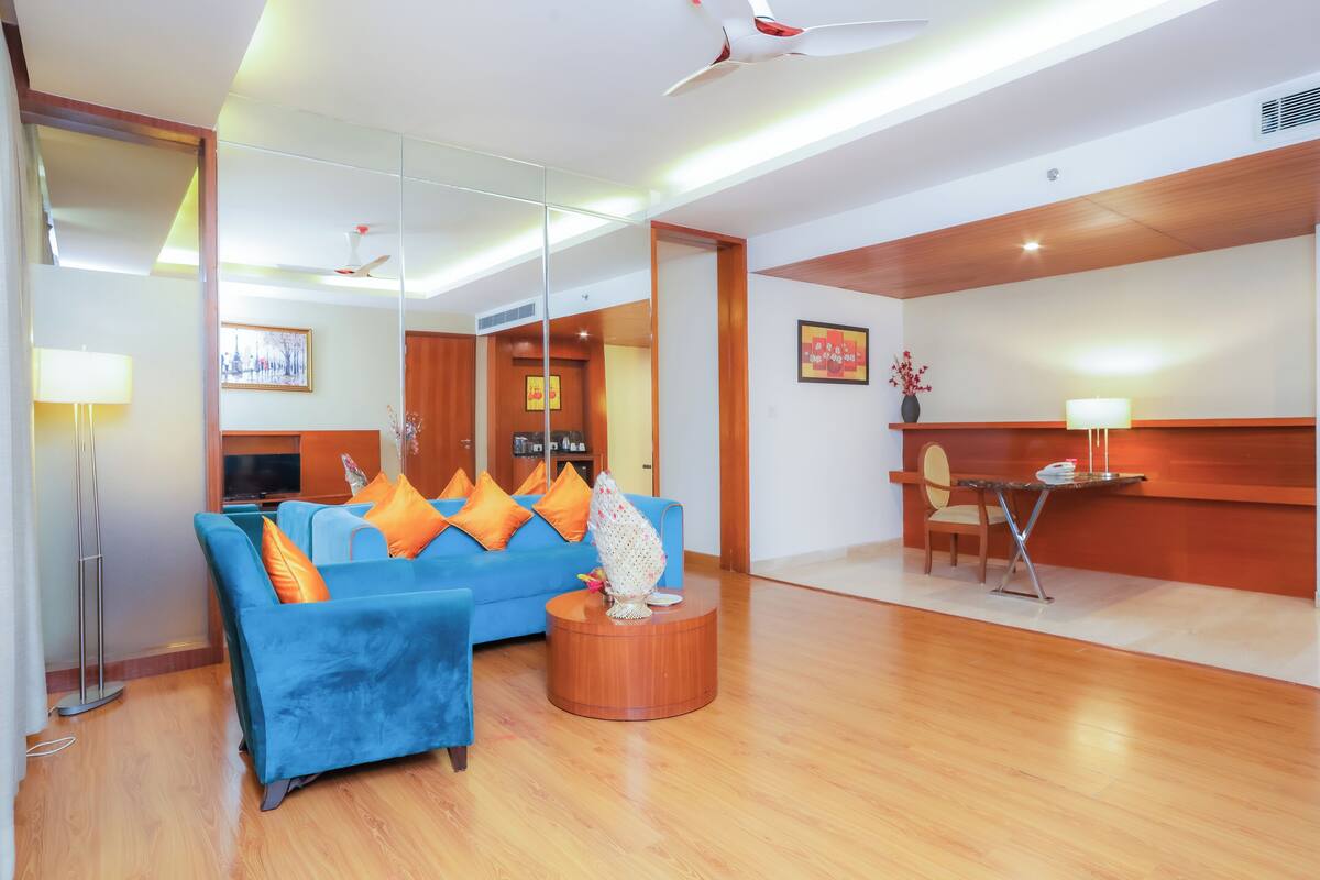 A modern hotel lobby with a blue sofa, wooden flooring, and a reception desk.