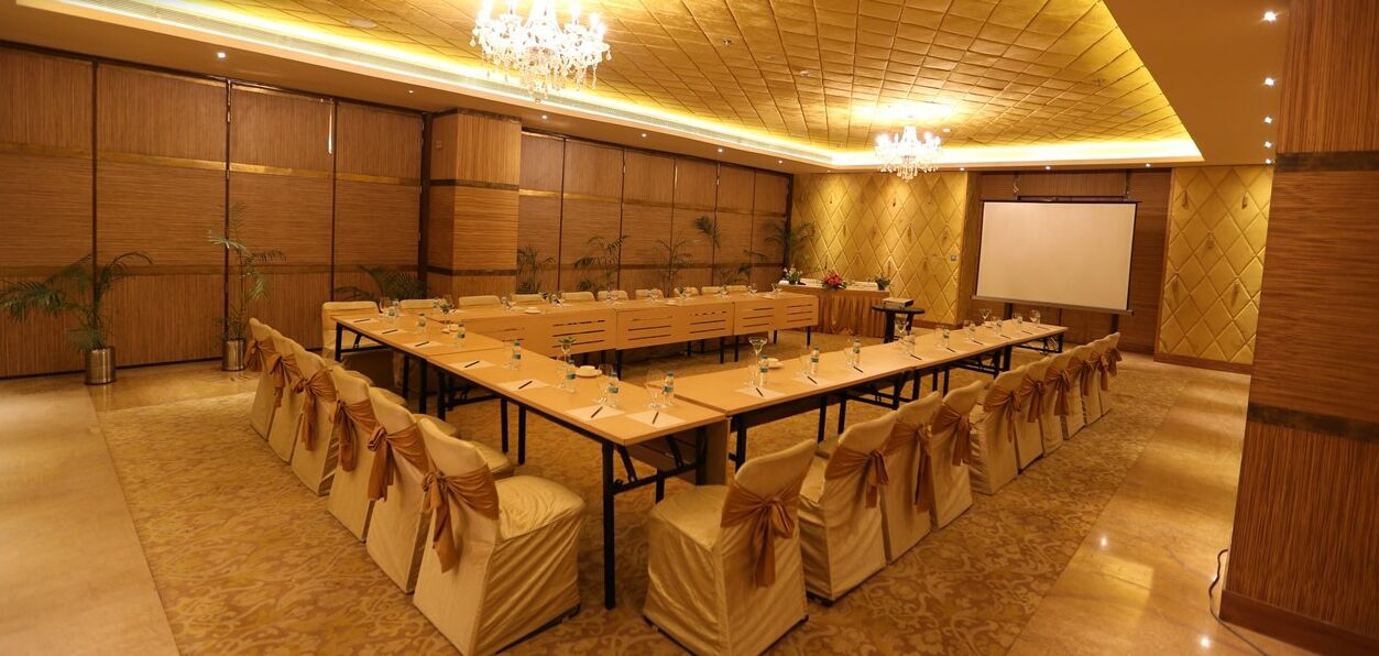 A conference room with a long table, chairs, and a projector screen.