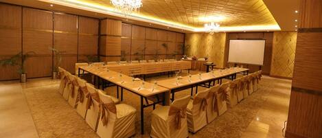 A conference room with a long table, chairs, and a projector screen.