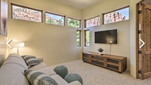 Un salon avec un canapé, des coussins, un téléviseur et un meuble en bois.