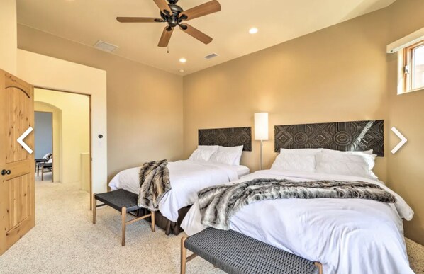 A bedroom with two beds, a ceiling fan, and a wooden door.