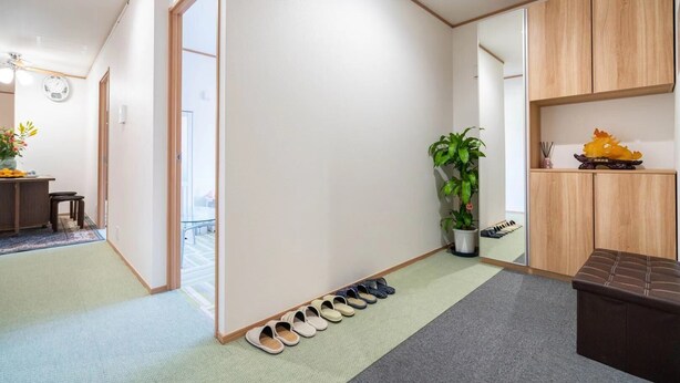 A modern hotel room with a large window, a potted plant, a wooden cabinet, and a shoe rack. - 1 bedroom apartment in saitama (川口市西川口)