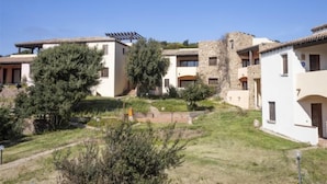 Un quartier résidentiel composé de plusieurs maisons, dont certaines ont des murs en pierre et d’autres présentent un style moderne, le tout entouré de verdure et sous un ciel dégagé.