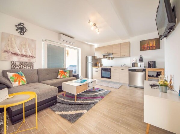 A modern living room with a sofa, coffee table, and a small dining area.