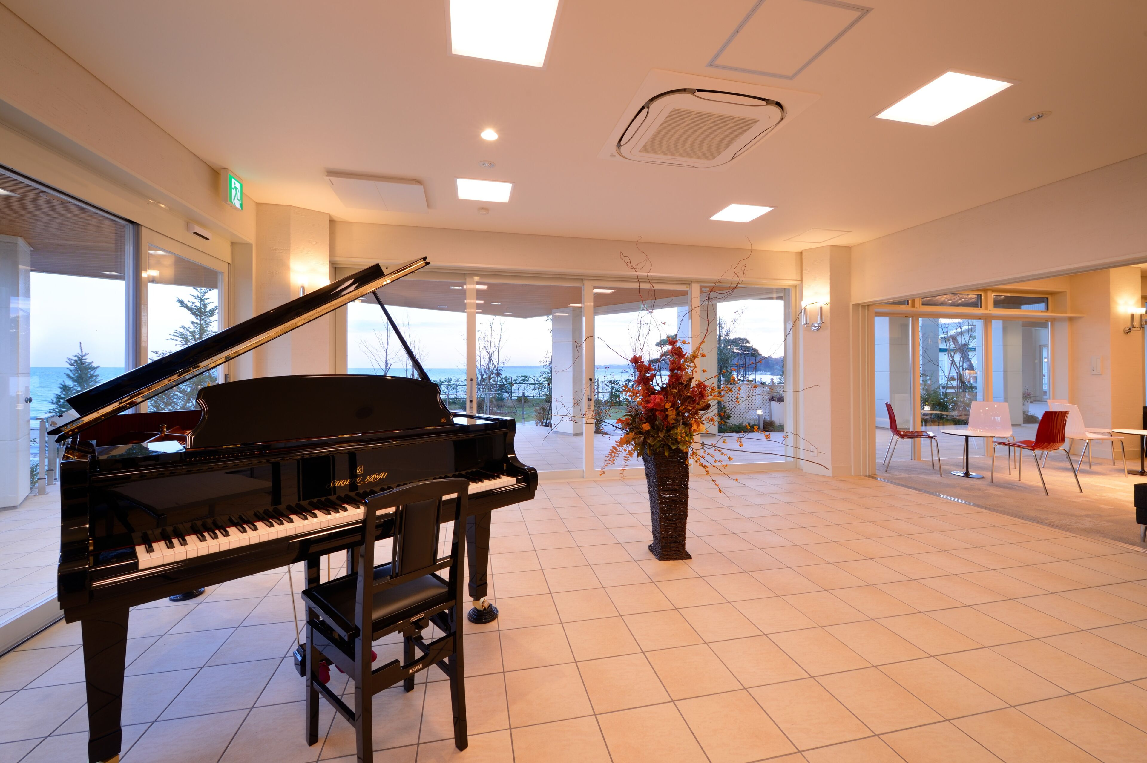 A spacious room with a grand piano, large windows, and a view of the outdoors.