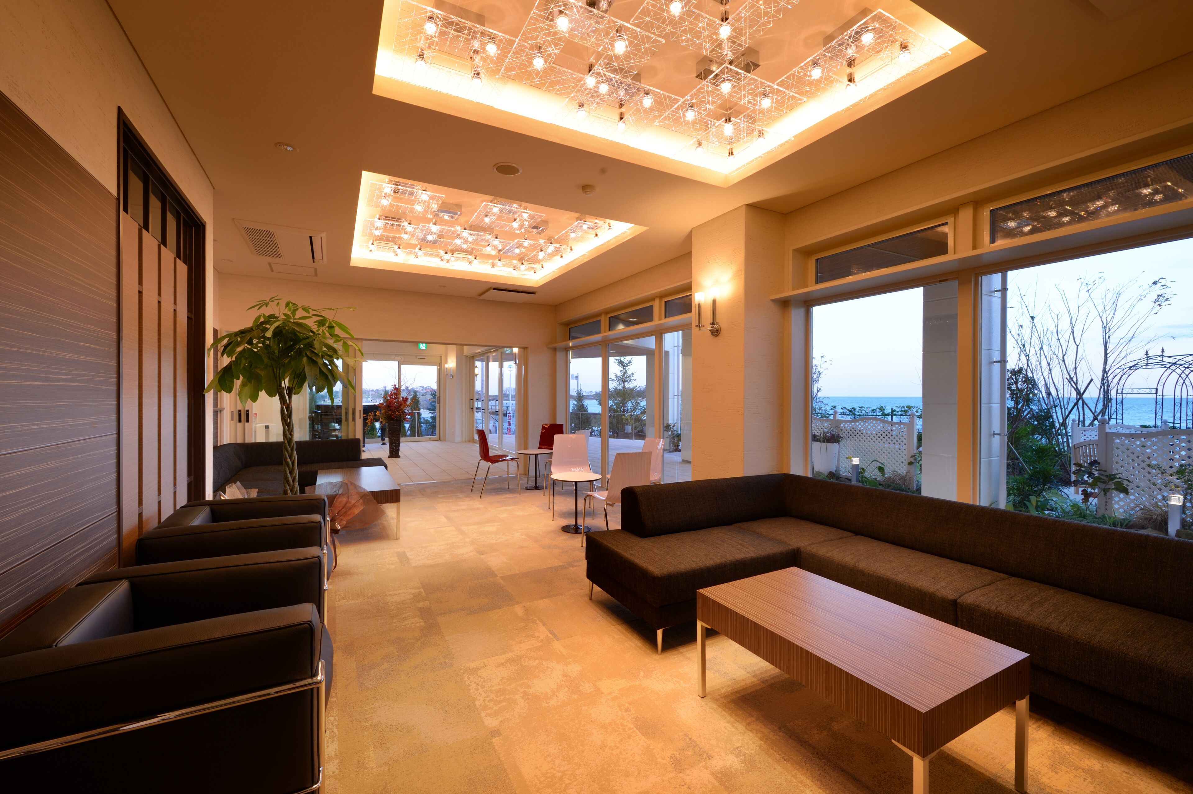 Un interior moderno con una amplia zona de estar, una mesa de madera y grandes ventanales que ofrecen vistas.