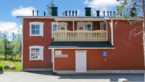 A two-story building with a red exterior, a balcony with a white railing, and a door labeled "OUTPAILAKKA". - Outapailakka j 12 by Interhome (Inari)