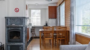 A compact kitchen with a built-in stove, wooden cabinets, and a dining area with a table and chairs. - Outapailakka j 12 by Interhome (Inari)