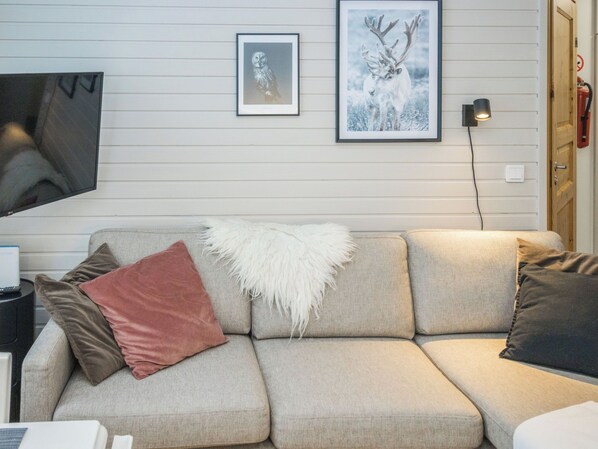 A beige sofa with a white furry throw, a brown pillow, and a black pillow.